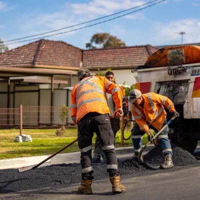 workers straightening bitumen on road