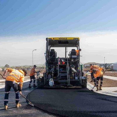 excavation machine and workers making new bitumen road